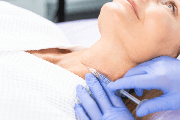 patient lying down receiving injectables to help with wrinkles on the neck
