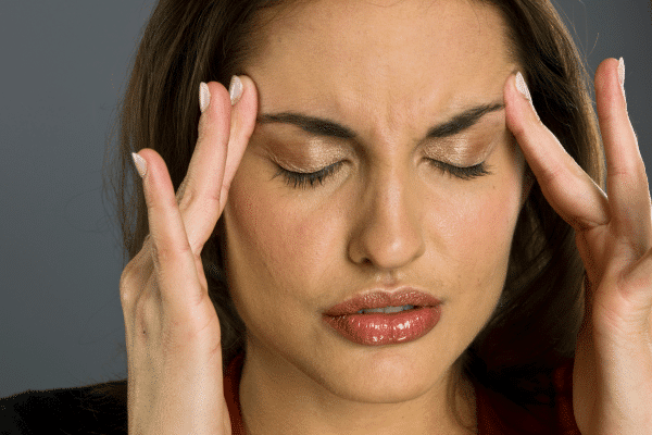 patient having a migraine and putting her fingers to her temples to relieve the pain